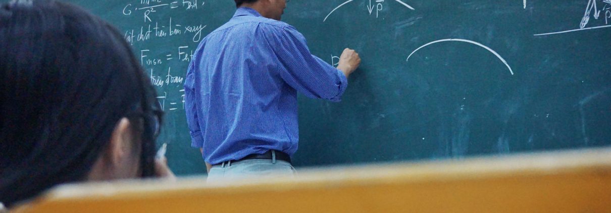 College professor writing on chalkboard