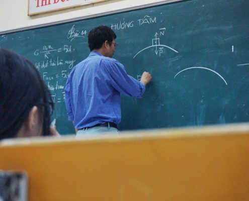 College professor writing on chalkboard